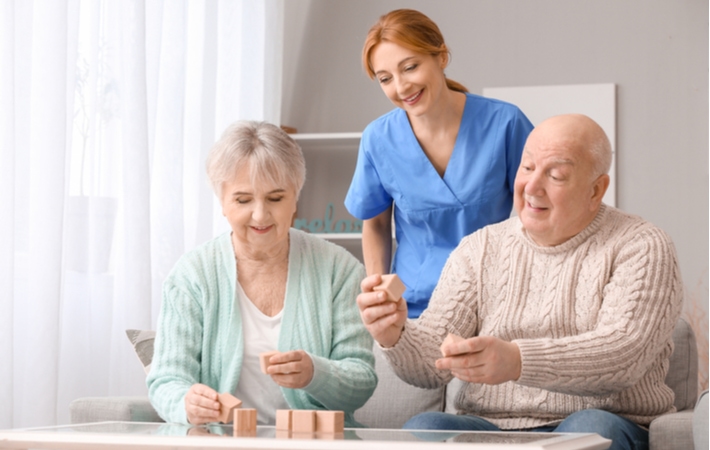 A senior couple working with a caregiver to complete activities geared towards improved memory loss