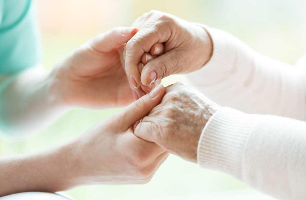 Closeup of hands of a young nurse holding hands of a senior lady.